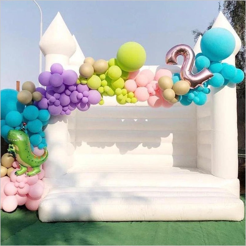 White bounce house with pastel balloon garland and birthday decorations