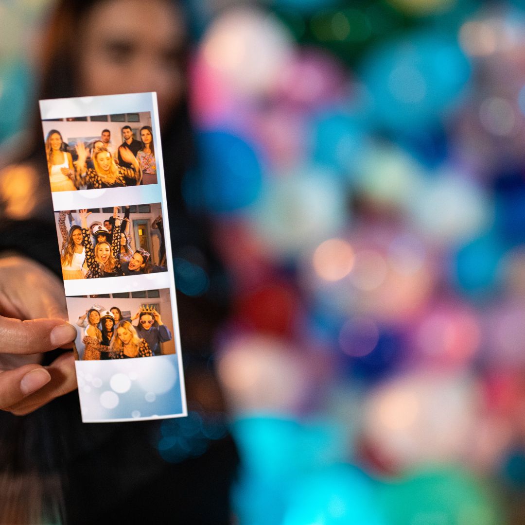 Close-up of printed photo booth strip held in hand with blurred background
